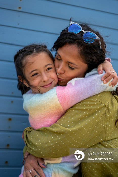 Smiling mother and daughter (8-9) hugging outdoors