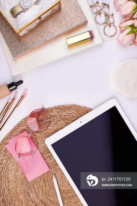 feminin flatlay topview with ipad on basket background with copy space pink roses golden notebook sunglasses lipstick eyeshadow cosmetics