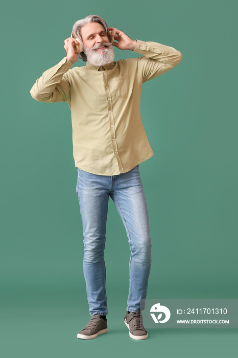 Bearded senior man in headphones on green background