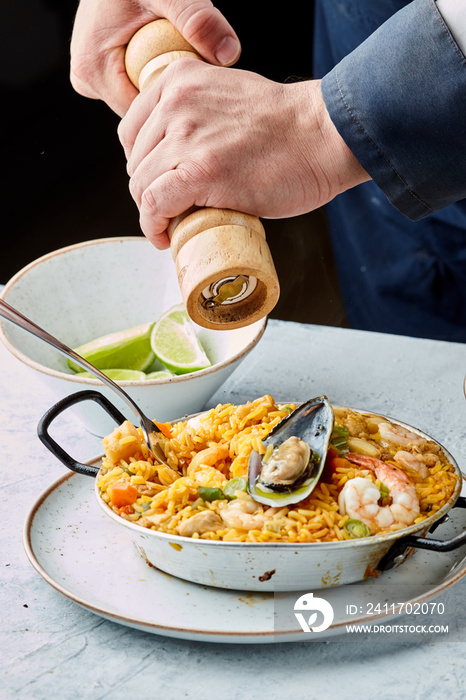 chef adding pepper to paella traditional spanish dish