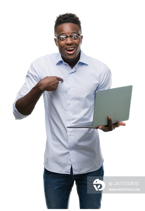 Young african american businessman using computer laptop with surprise face pointing finger to himself