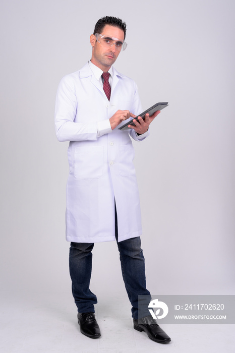 Full body shot of handsome man doctor with protective glasses using digital tablet