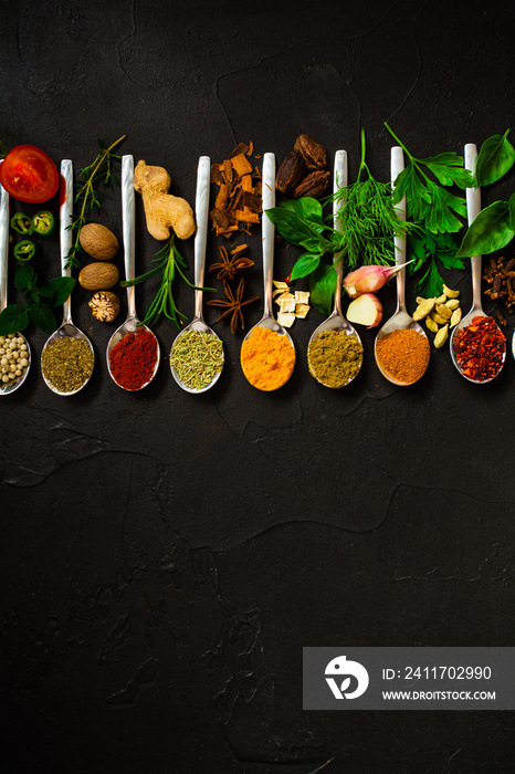 Colourful various herbs and spices for cooking on dark background.