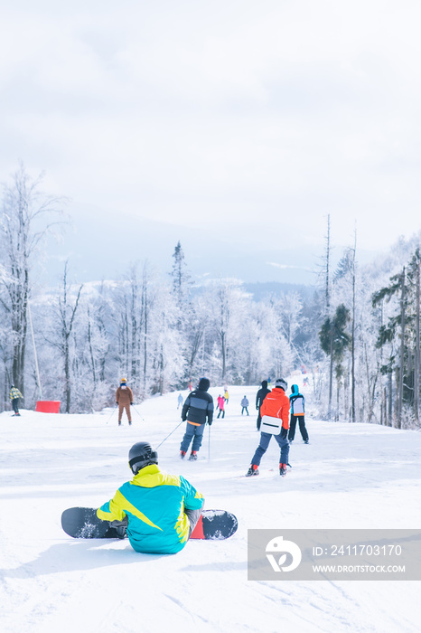 man sitting on the top of the hill enjoying view. snowboarding. winter sport activities