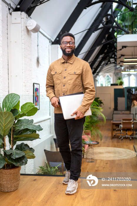 Portrait of smiling man holding laptop at home