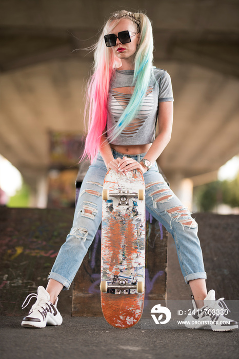 Beautiful and fashion young woman posing with a skateboard