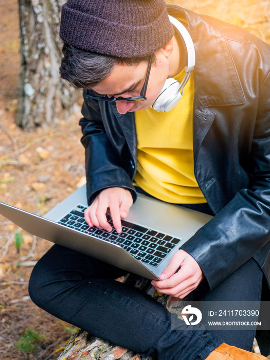 Latino teenager with yellow sweater and laptop. New technology concept.