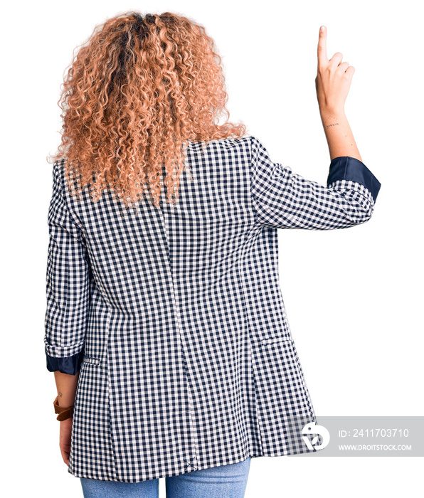 Young blonde woman with curly hair wearing business jacket and glasses posing backwards pointing ahead with finger hand