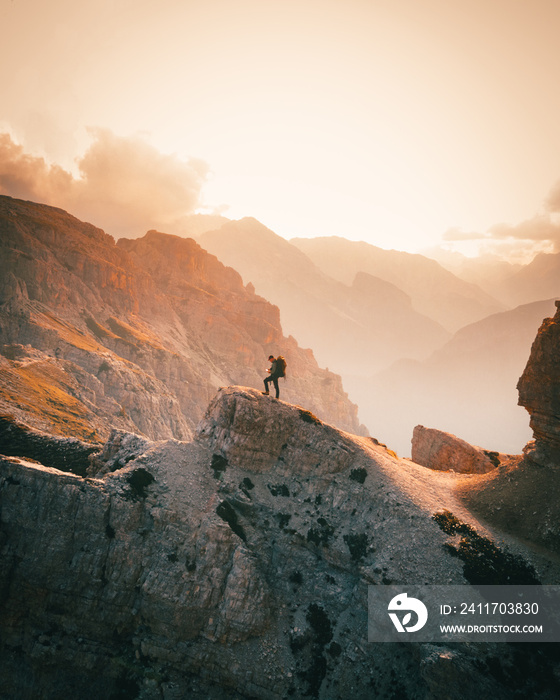 hiker on top of mountain in dolomites at cadini di misurina during sunset in summer