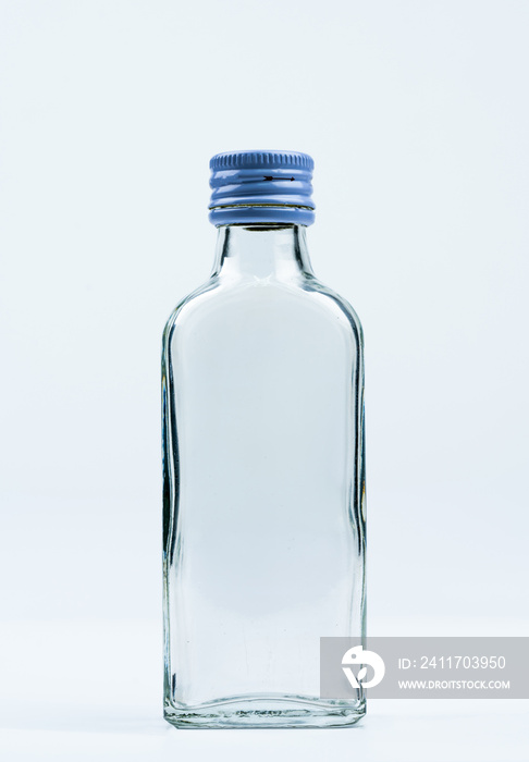 Empty transparent glass bottle with closed aluminum cap isolated on white background with blank label and copy space. Use for beverage or medicine product design template. Glass bottle packaging.