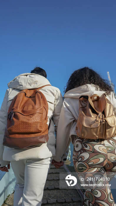 Rear view of couple with backpacks walking outdoors