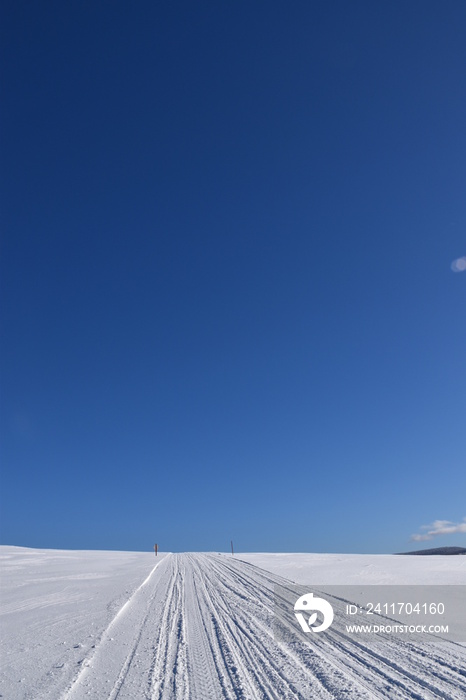 A snowmobile trail under a blue sky, Québec, Canada