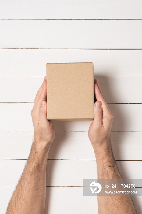 Small parcel in male hands. Top view. White table on the background