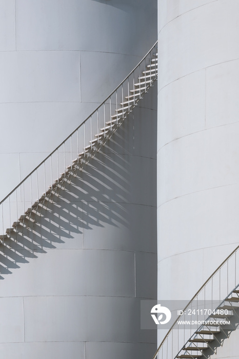 Sunlight and shadow on spiral staircases surface of 2 oil storage fuel tank in vertical frame