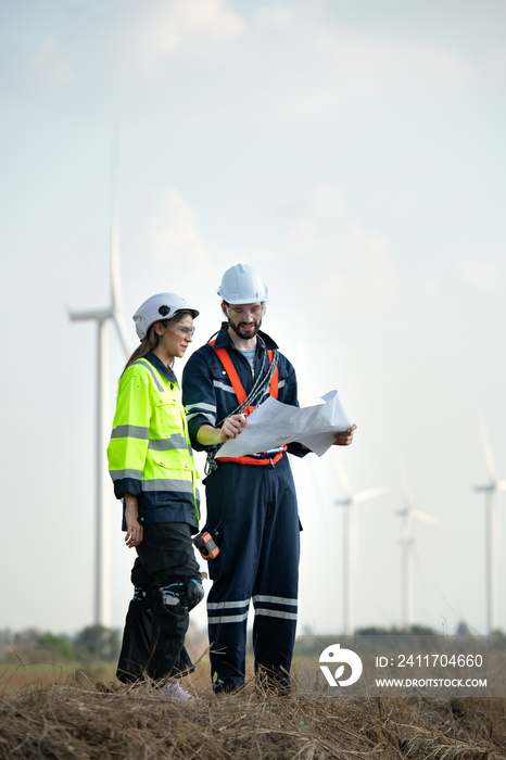 Man and female engineer stationed at the Natural Energy Wind Turbine site. with daily audit tasks of major wind turbine operations that transform wind energy into electrical electricity