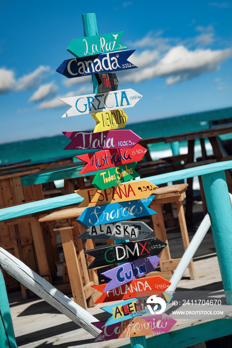 Colorful wooden direction signpost with destination countries at Playa El Tecolote near La Paz, Mexico