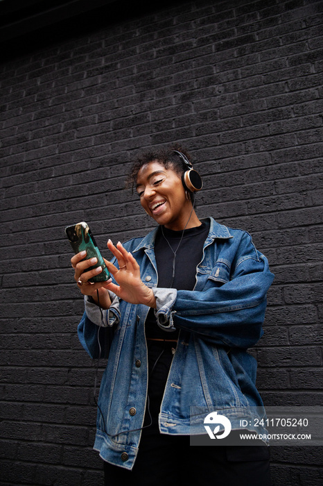 Curvy mixed-race woman with vitiligo taking a selfie in front of a black wall