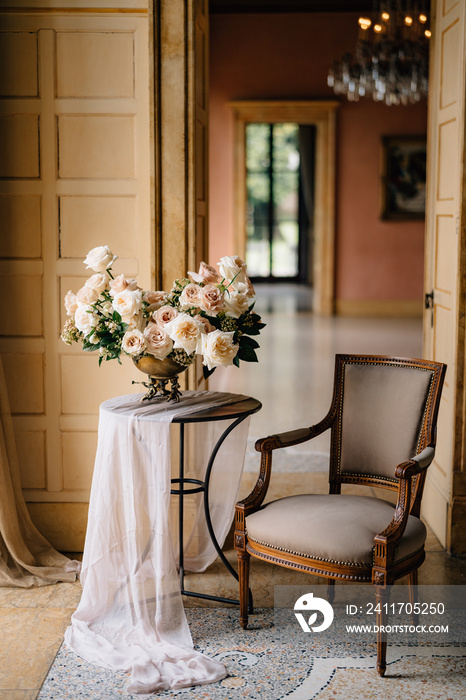 bouquet of tender cream roses in copper vase on the table in the elegant room with vintage armchair