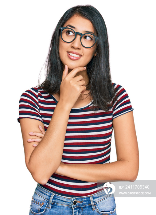 Beautiful asian young woman wearing casual clothes and glasses with hand on chin thinking about question, pensive expression. smiling with thoughtful face. doubt concept.