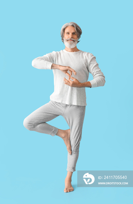 Mature man practicing yoga on color background