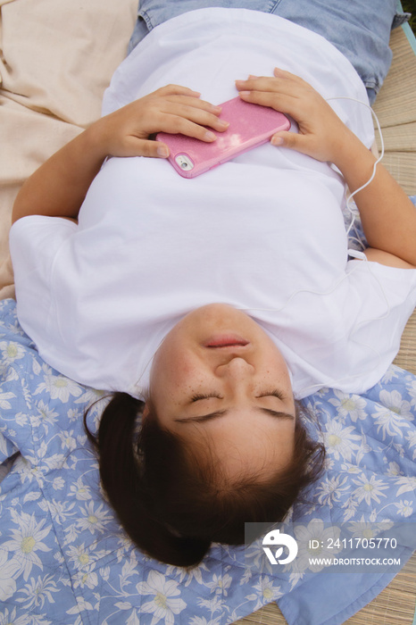 Curvy girl with Down syndrome listening to music in the park