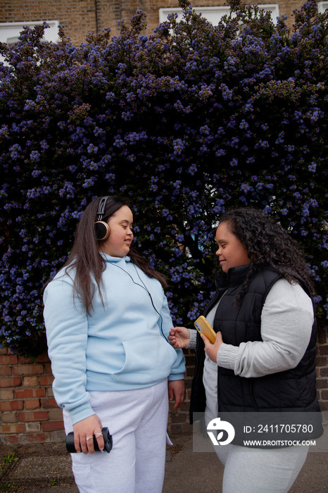 Two plus-sized women with Down Syndrome in workout clothes listening to music