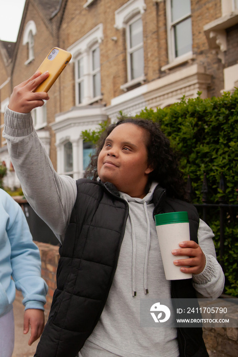 Two curvy women with Down Syndrome taking selfies in with their coffees