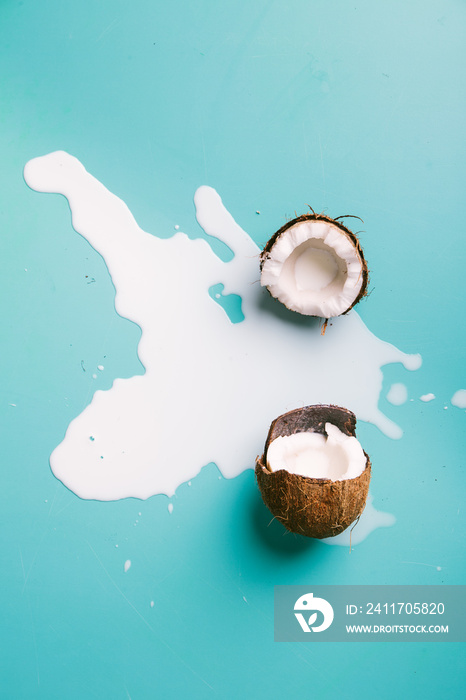 Coconut milk with a straw on turquoise background. Half of coconut on blue background. Tropical fruit concept.