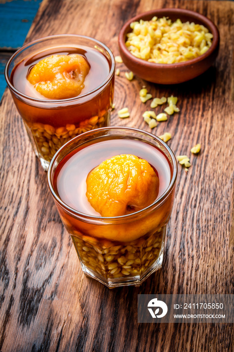 Mote con huesillo. Traditional Chilean drink made from cooked husked wheat and dried peach on wooden board, rustic blue background