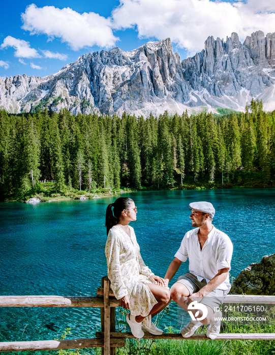 Carezza lake, couple men and woman on vacation in the Italian Dolomites Italy. Europe, Carezza lake Karersee with Mount Latemar, Bolzano province, South tyrol, Italy. The landscape of Lake Carezza