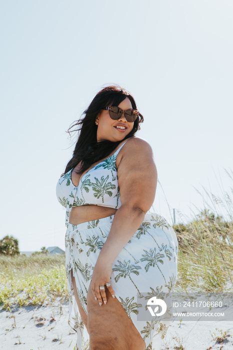 plus size African American woman looks over her shoulder smiling at the beach