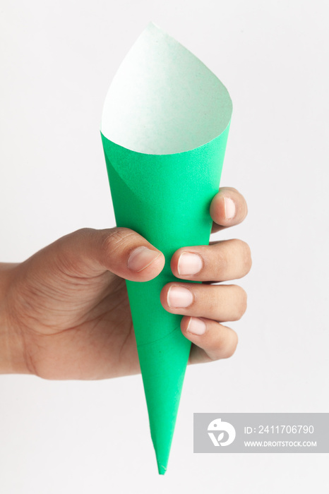 Close-up of empty green white color Paper cone bag, snack packaging, craft paper for wrapping fries and nuggets in street food,  brown paper cone holding in hand isolated over white