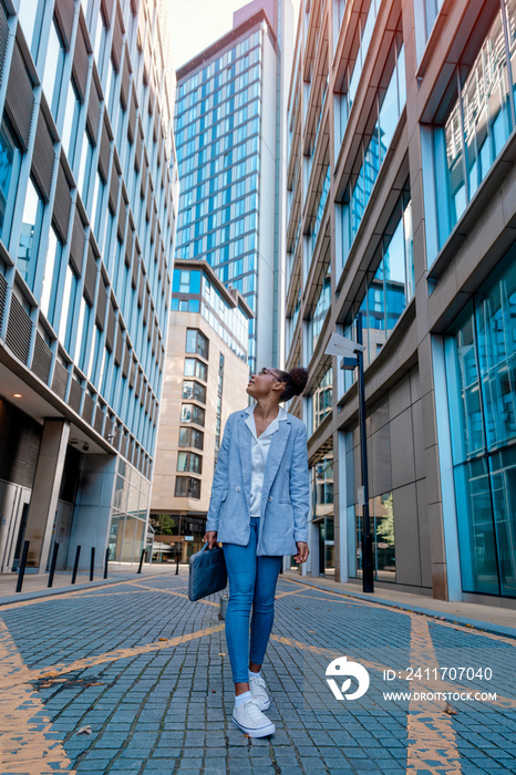 a woman in casual clothes walks around the city, lost among the skyscrapers