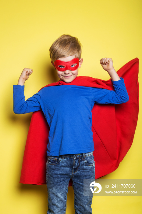 Boy in red super hero cape and mask. Superman. Studio portrait over yellow background