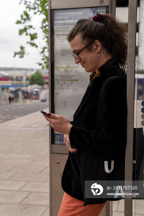 Young man using phone while waiting at bus stop