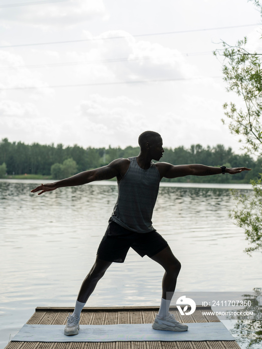 Man practicing yoga by lake