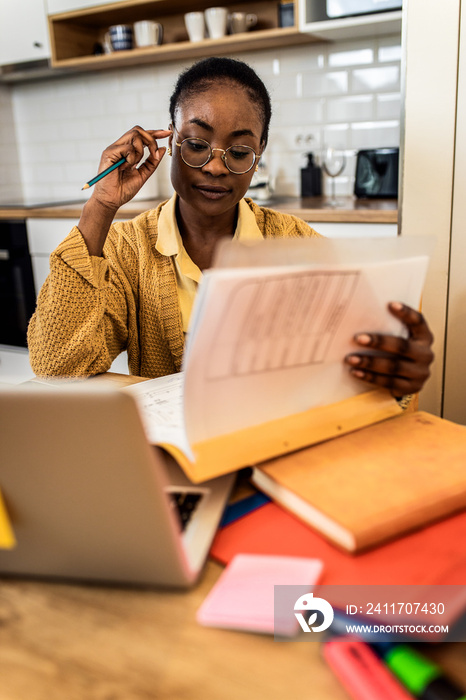 Young African American female student studying at home using laptop.