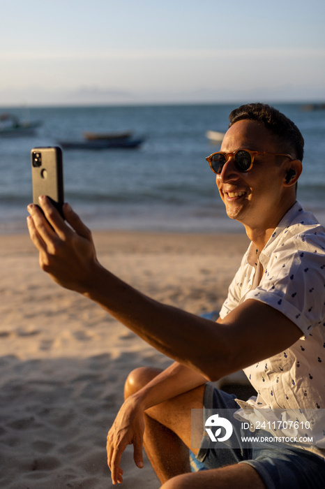 Man sitting at beach and using smart phone