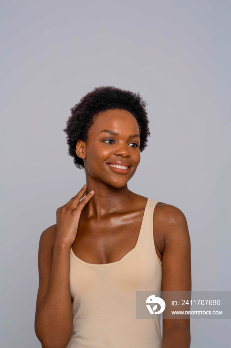 Studio portrait of smiling woman in cream colored tank top