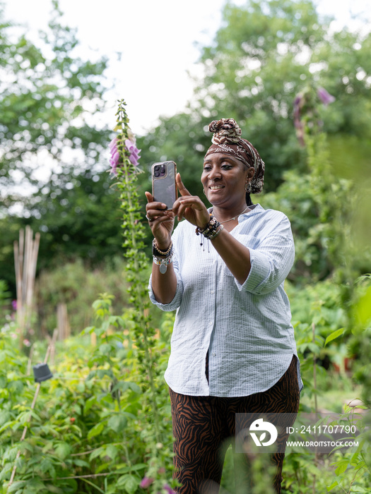 Mature woman photographing flowers in garden