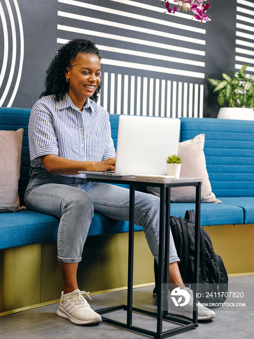 Woman using laptop in office lounge area