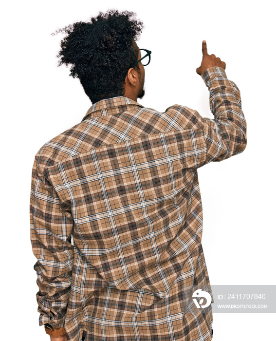 Young african american man with beard wearing casual clothes and glasses posing backwards pointing ahead with finger hand