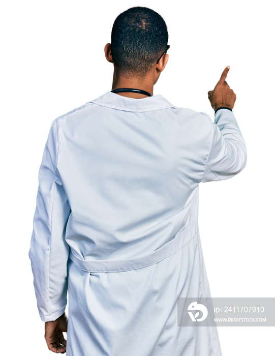 Young african american man wearing doctor uniform and stethoscope posing backwards pointing ahead with finger hand