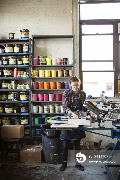 Woman operating screen printing machinery in factory