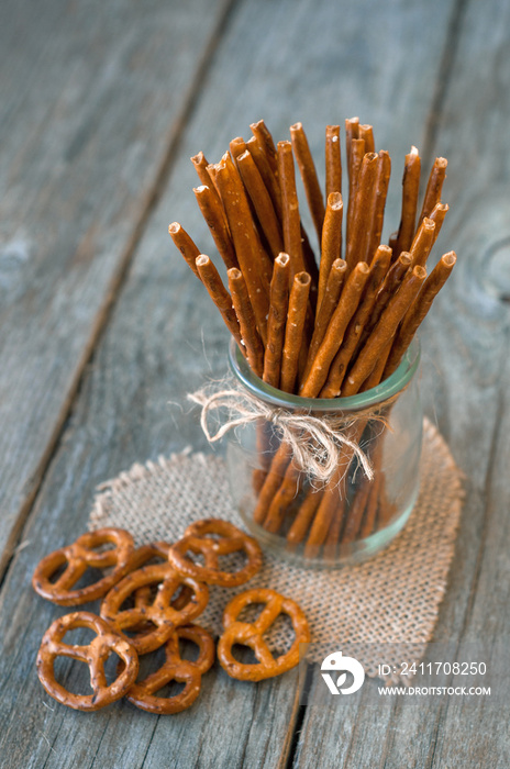 Salted sticks in a glass and on wooden table, with a selective focus.