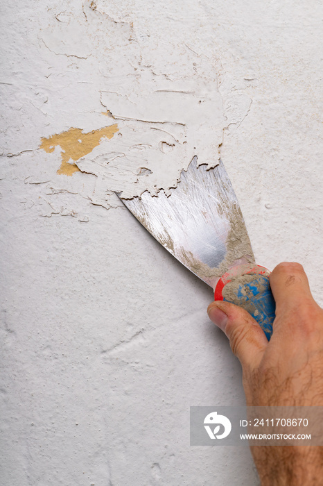 Removing old paint from the wall with a metal spatula. Small painting works at home.