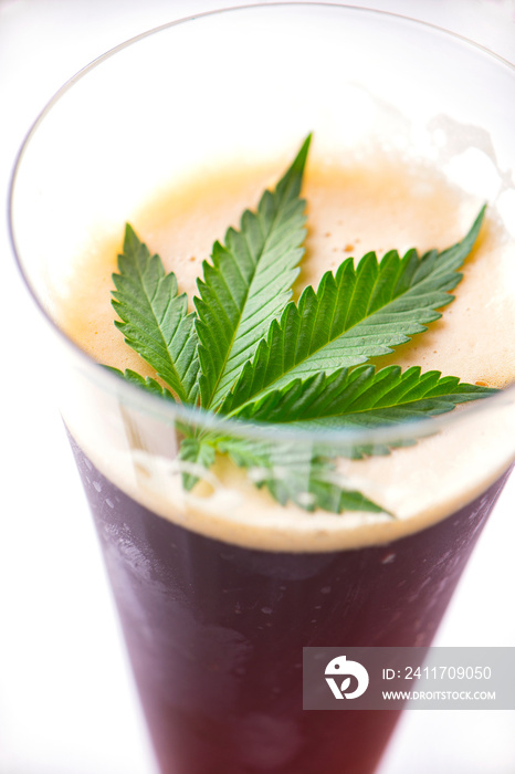 Detail of cold glass of beer with cannabis leaf isolated over white