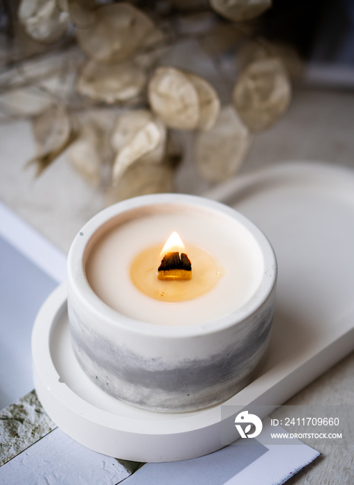 Home decoration with burning aromatic candle, white interior decor
