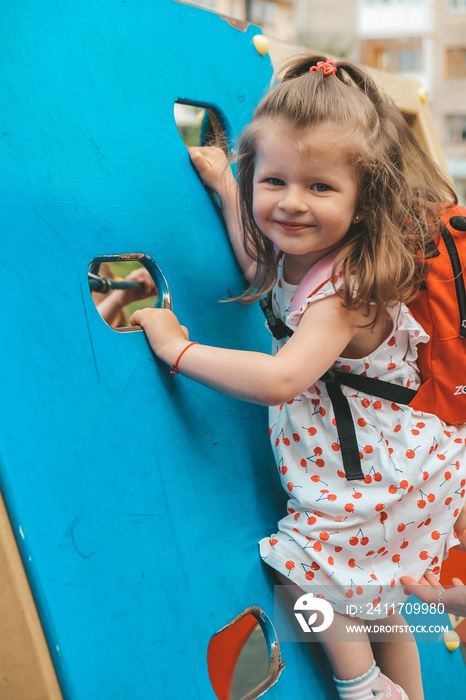 Kid on obstacle course. Pretty happy young girl playing outside in playground. Portrait Of Cute Girl Playing At Playground