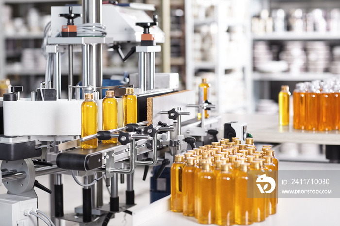 Bottles filled with soap yellow liquid standing on conveyor belt in factory. Automated process of creation soap on factory. Bottles with yellow thick substance standing in row going to be twisted